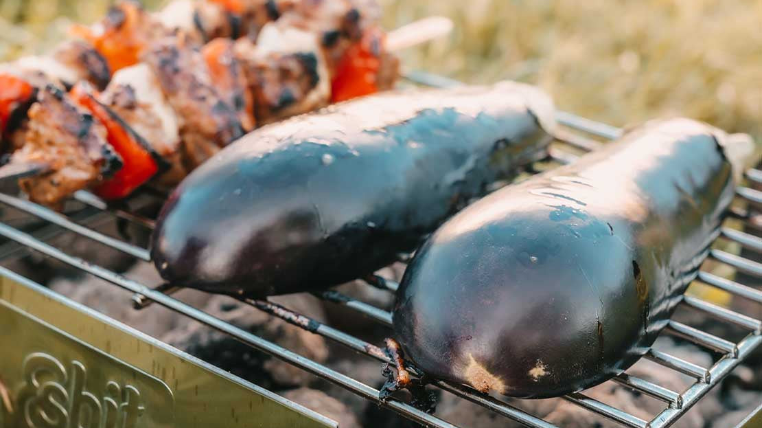 Esbit Mehrweg-Holzkohlegrill aus Edelstahl beim Grillen von Aubergine