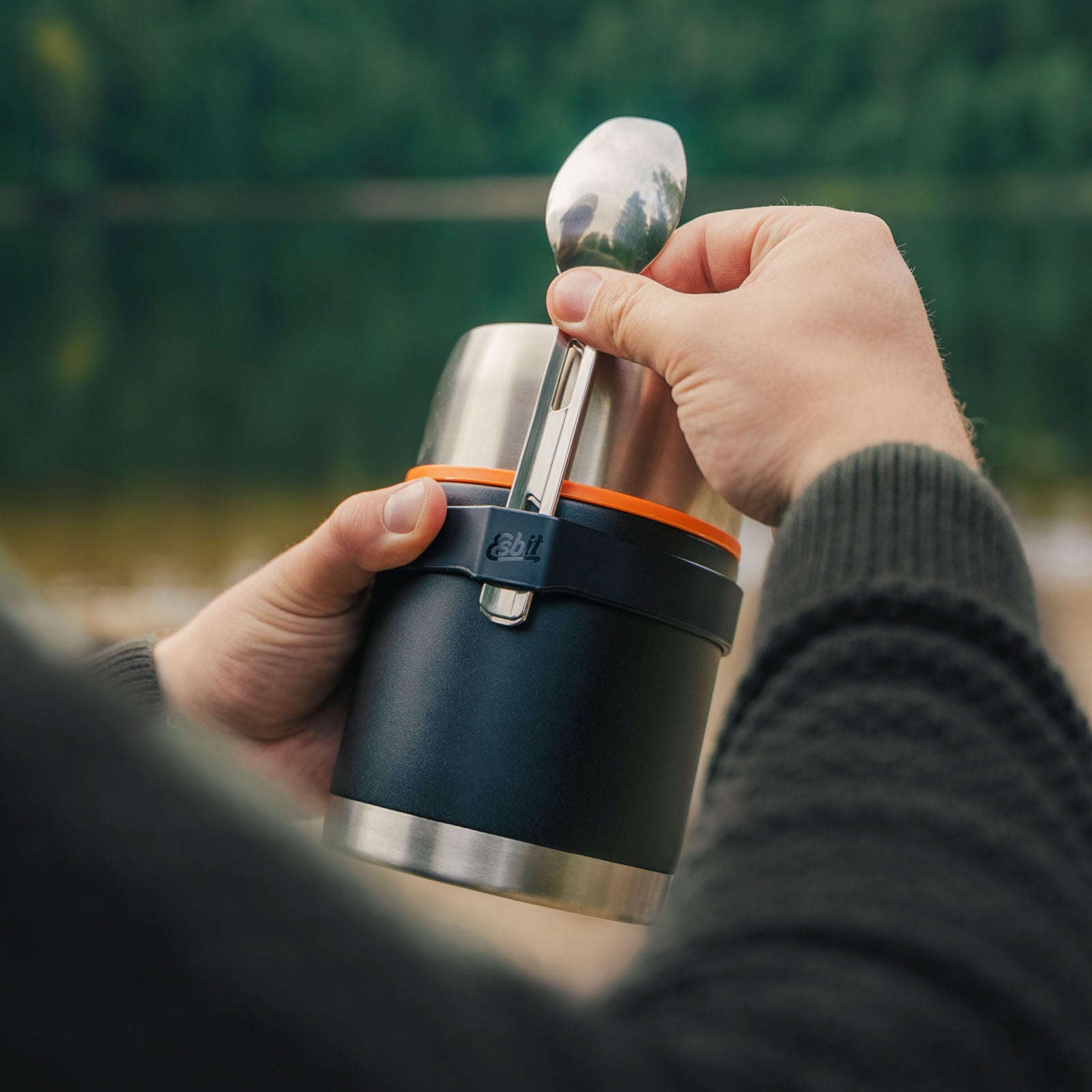 Person benutzt schwarzen Esbit Food Jug in der Natur