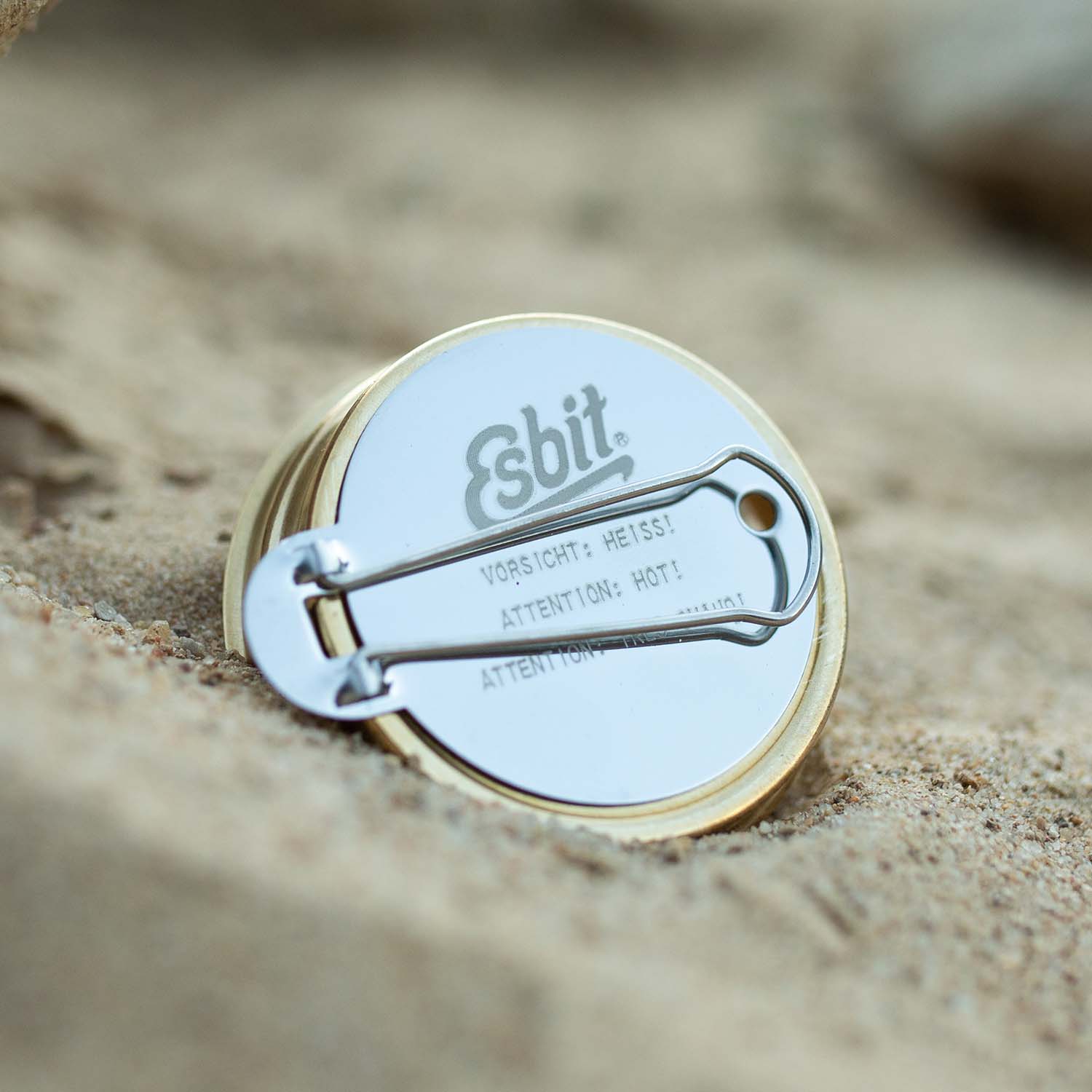 Esbit Spiritusbrenner AB300BR mit Klappbriff liegt im Sand.