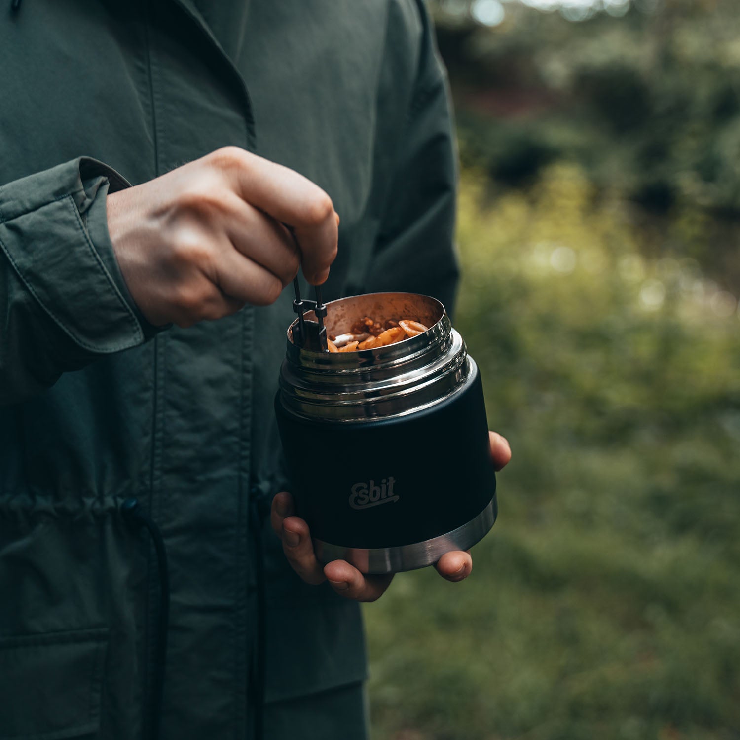 Frau isst Pasta aus dem SCULPTOR Thermobehälter in Schwarz.