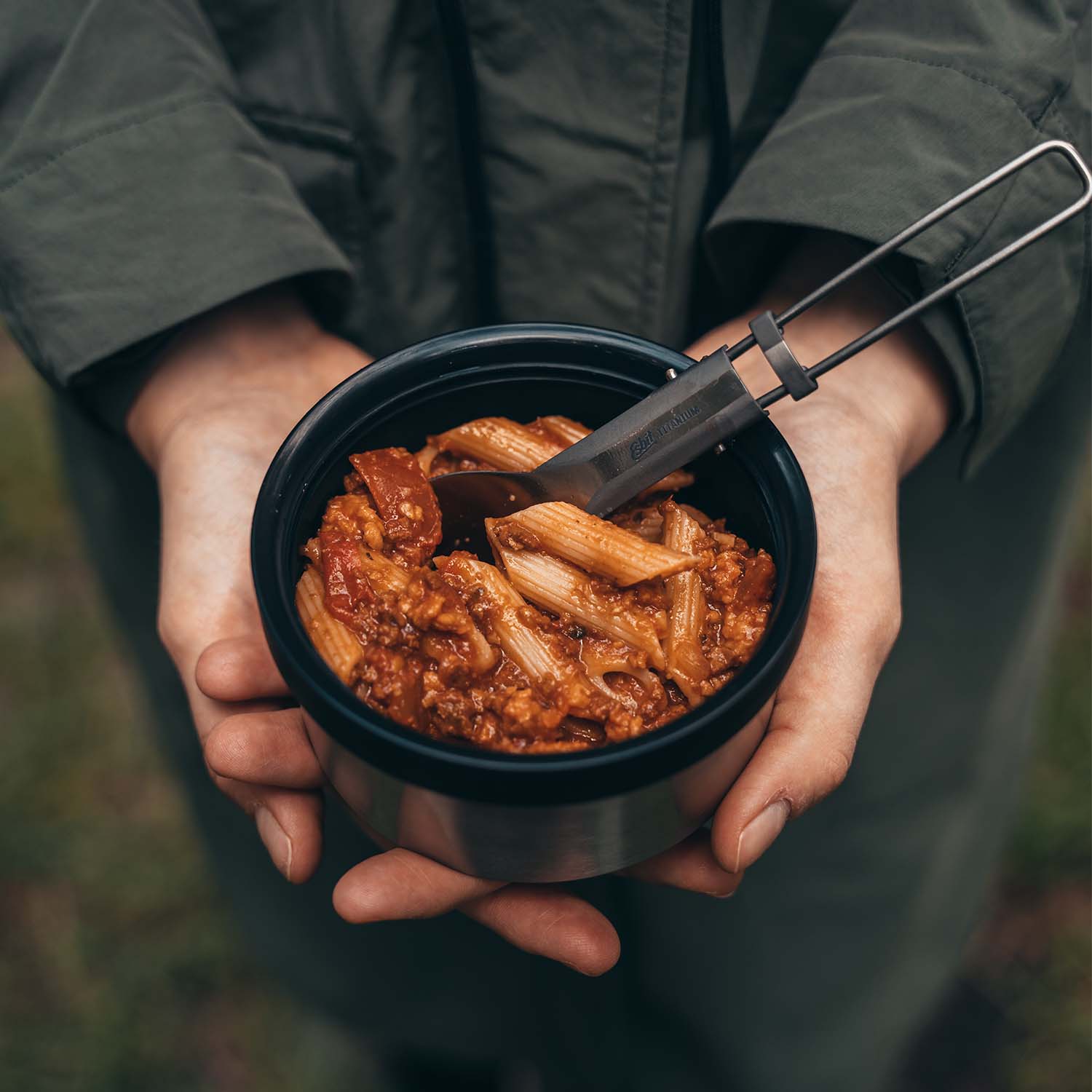 Frau nutzt den Deckel des SCULPTOR Thermobehälters in Schwarz als Schüssel für ihre Pasta Bolognese.