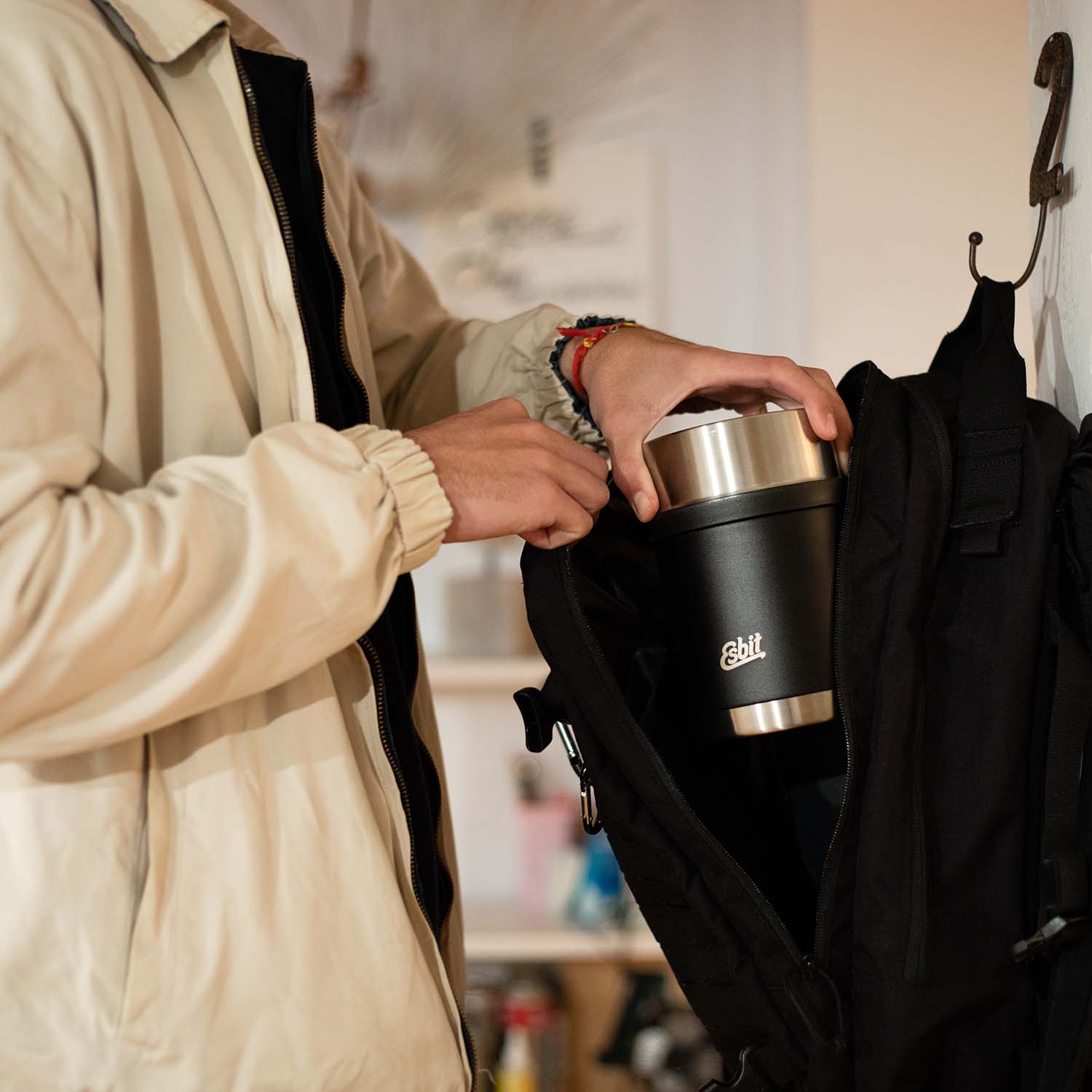 Mann packt den SCULPTOR Thermobehälter in Schwarz zuhause in seinen Rucksack.