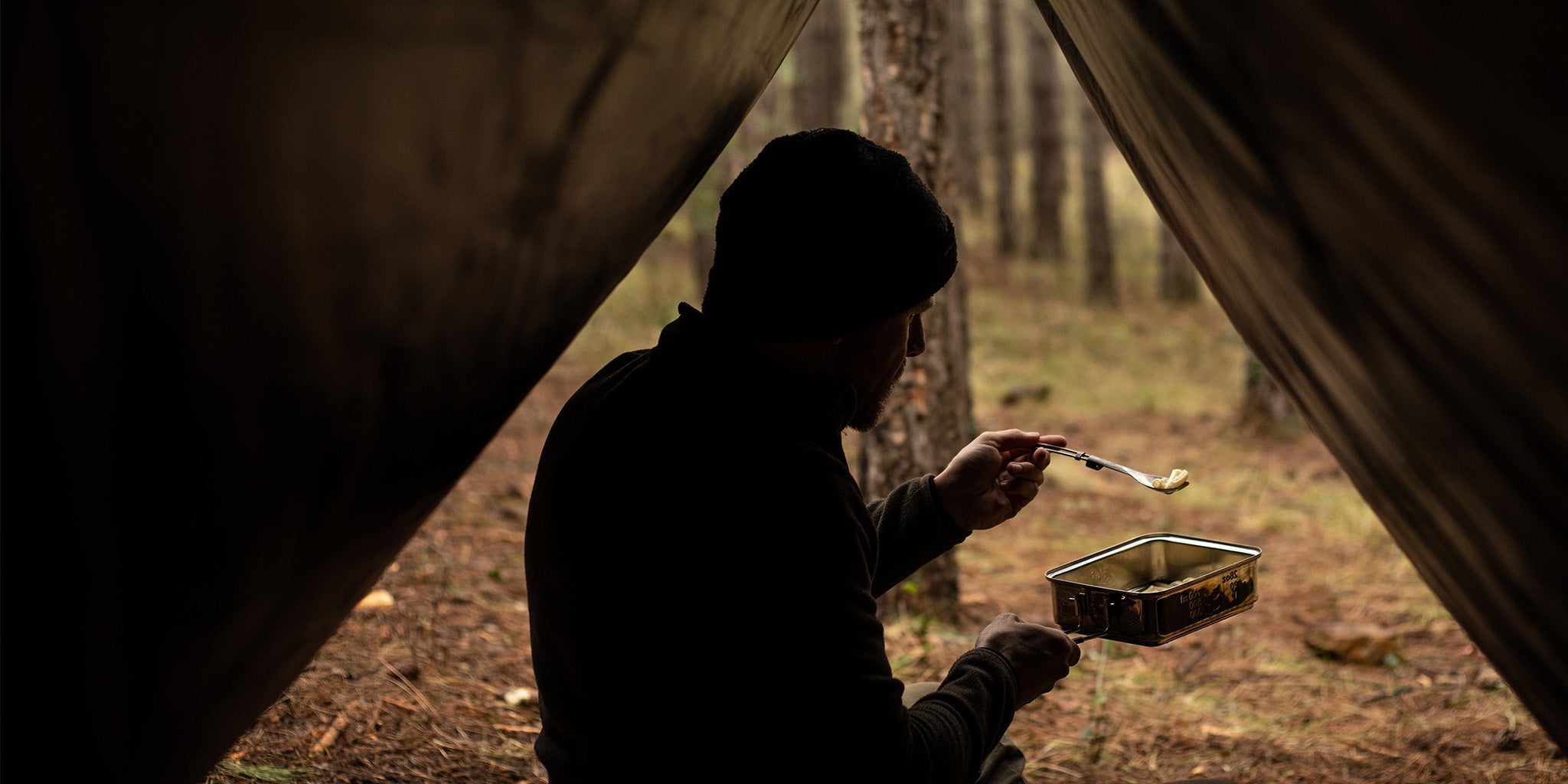 Mann sitzt im Zelt und isst Nudeln aus dem Edelstahl-Topf vom Trockenbrennstoff-Kochset CS1100ST.