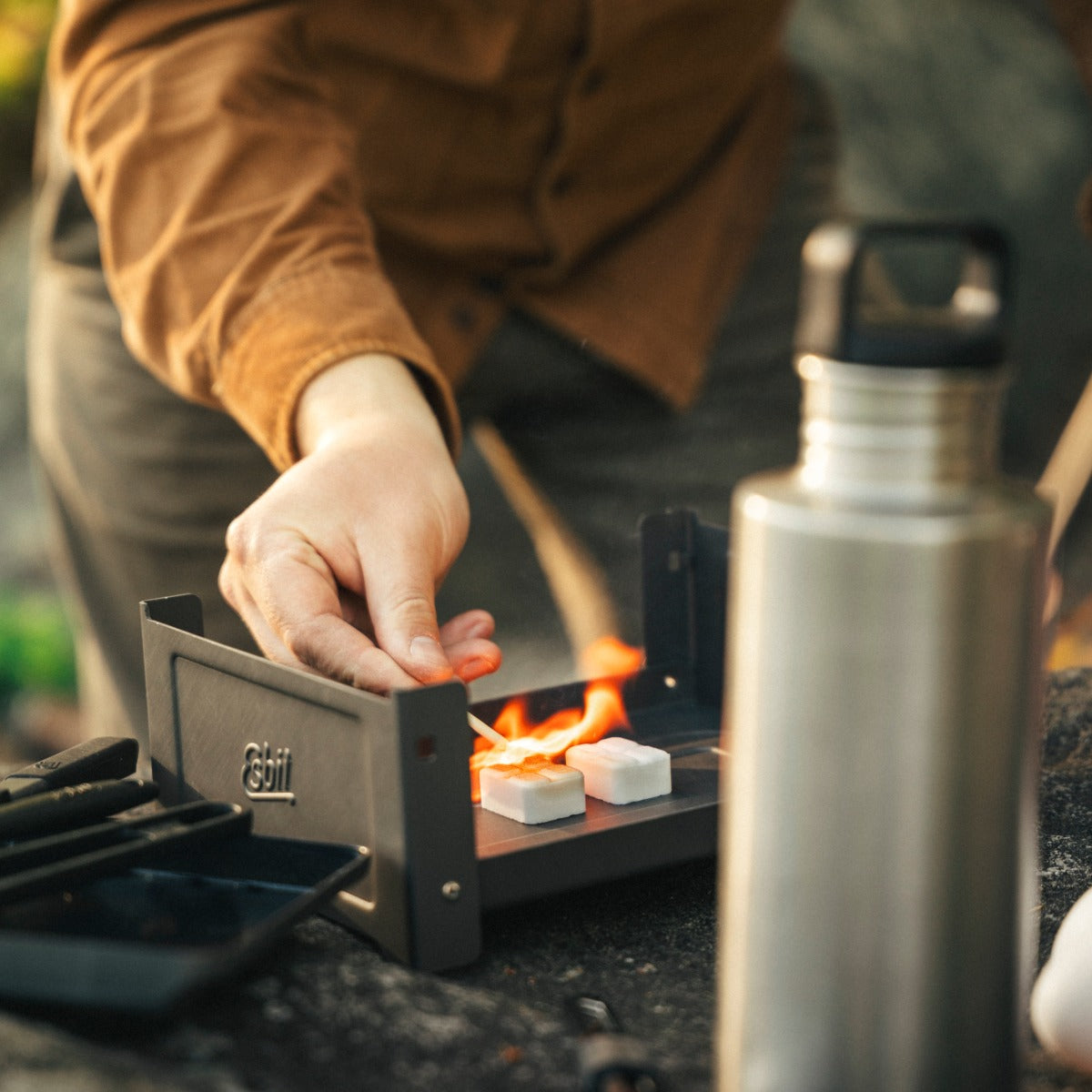 Person zündet Esbit Trockenbrennstoff Tabletten in dem Plancha Grill an