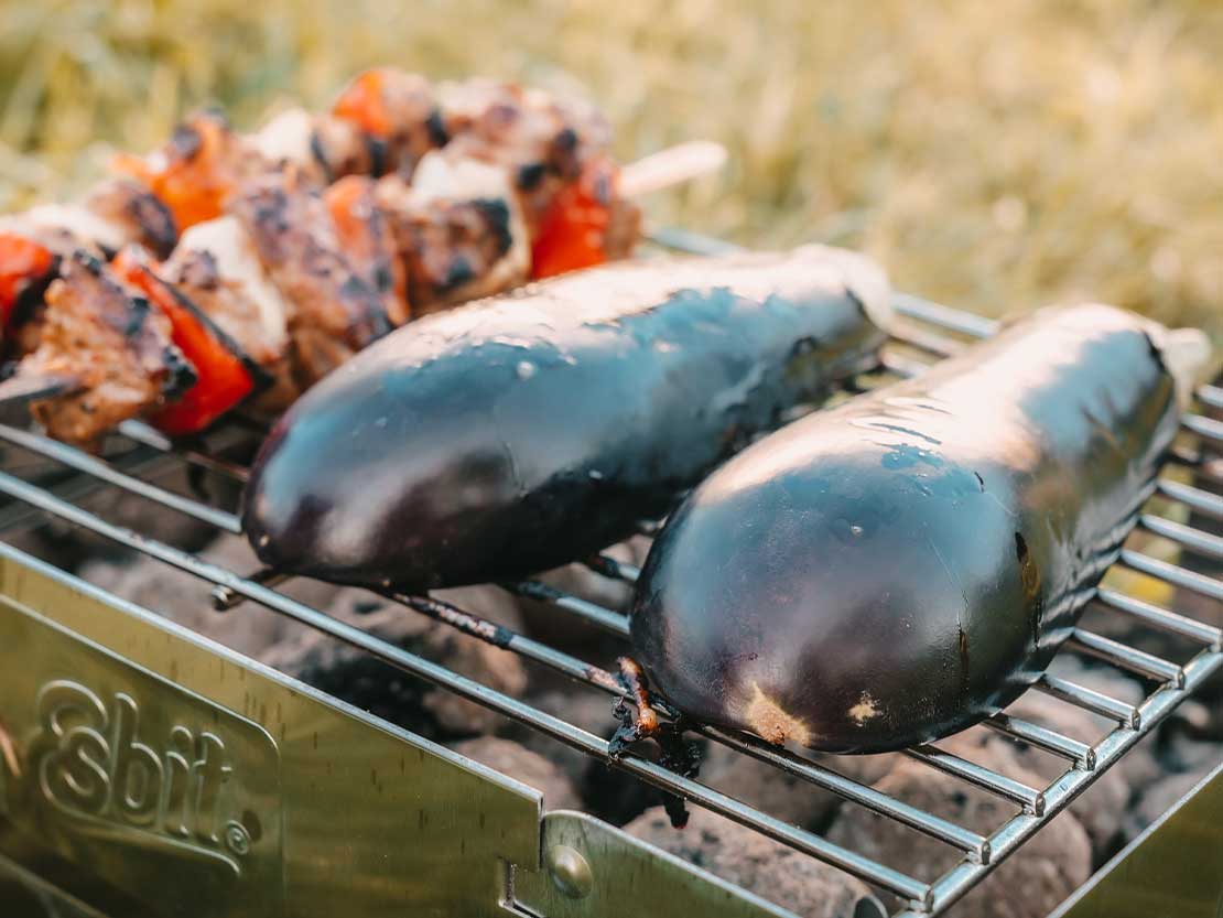 Esbit Mehrweg-Holzkohlegrill aus Edelstahl beim Grillen von Aubergine