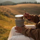 Frau hält den Esbit SCULPTOR Food Jug in Stone Grey und zieht den Löffel aus dem Silikonband.