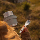 Frau hält den Esbit SCULPTOR Food Jug in Stone Grey und das passende Besteckset in der Hand 