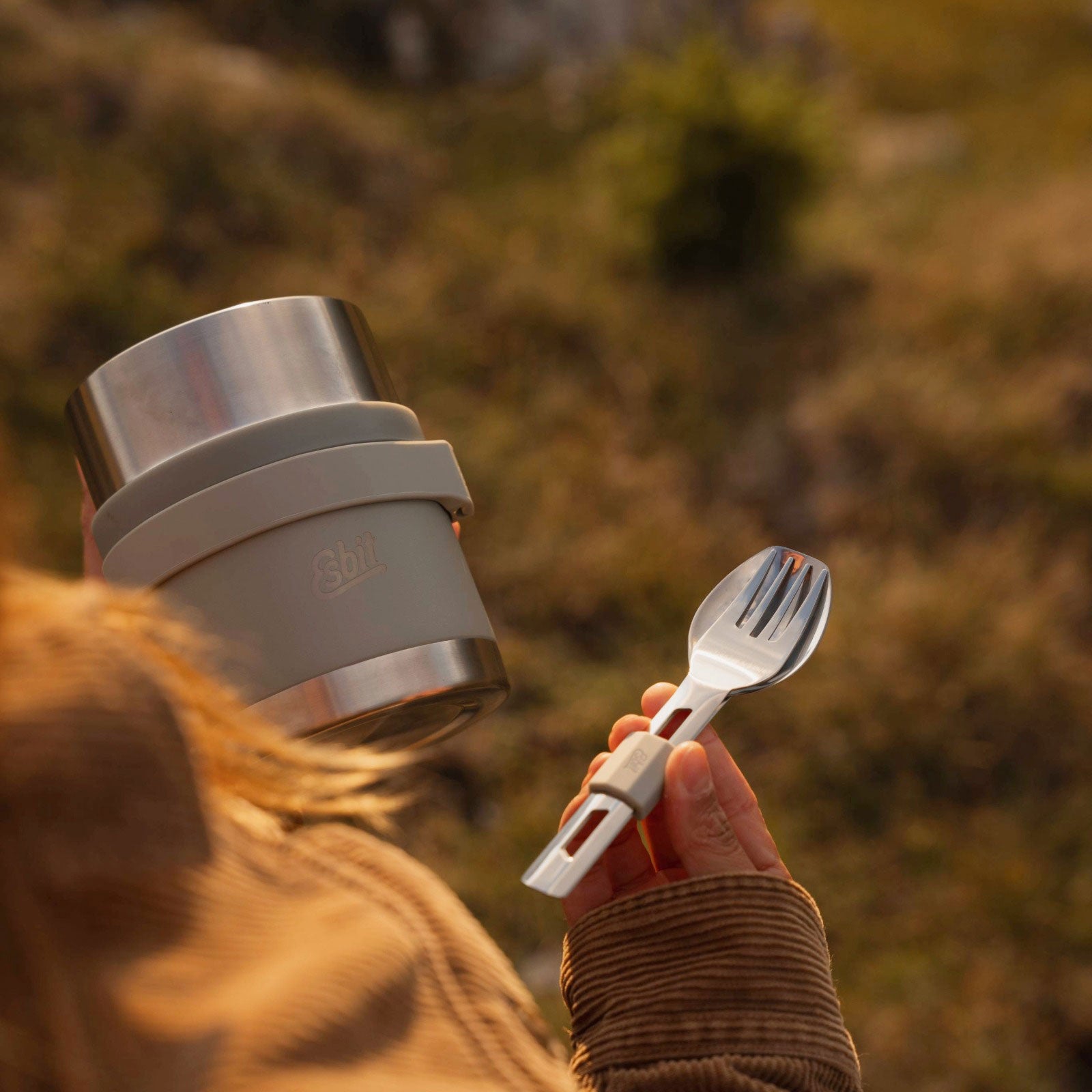 Frau hält den Esbit SCULPTOR Food Jug in Stone Grey und das passende Besteckset in der Hand 