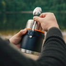 Person benutzt schwarzen Esbit Food Jug in der Natur