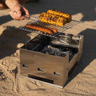Esbit Edelstahlgrill BBQ300S mit gegrilltem Maiskolben und Würstchen in einer Outdoor-Umgebung.