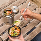 A person is eating pasta salad with the Esbit long-handled spoon from the lid of an Esbit Food Jug