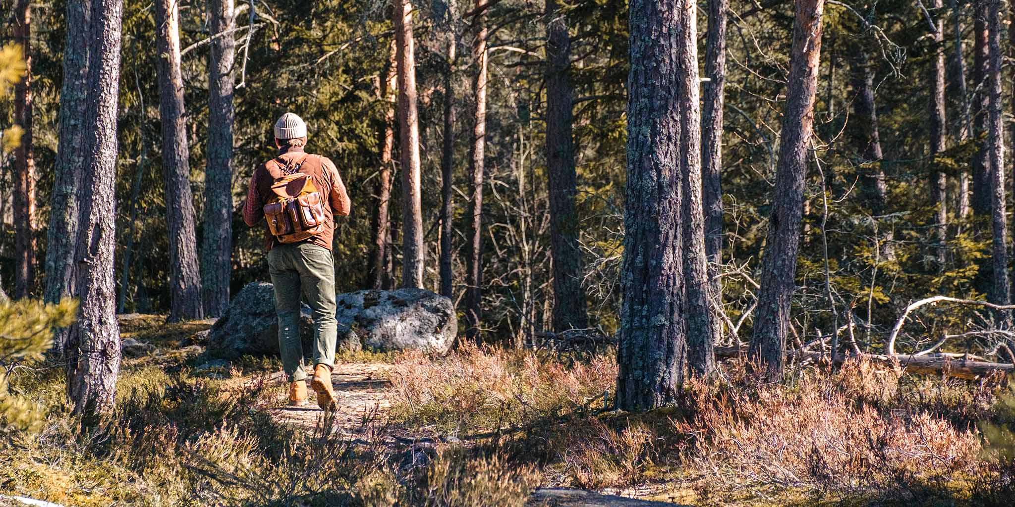 Mann mit Rucksack geht im Wald spazieren.