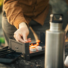 Person zündet Esbit Trockenbrennstoff Tabletten in dem Plancha Grill an 